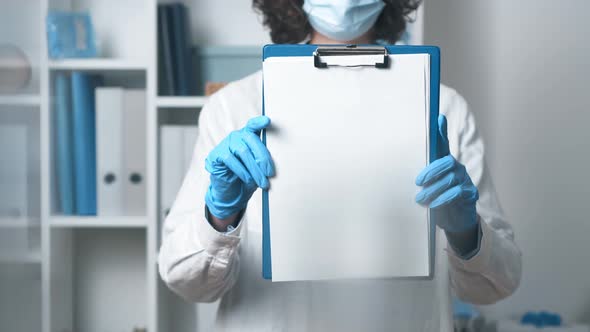 Woman Doctor Holding A White Sheet Of Paper. The Doctor's Hands Hold A Sheet Of Note Paper