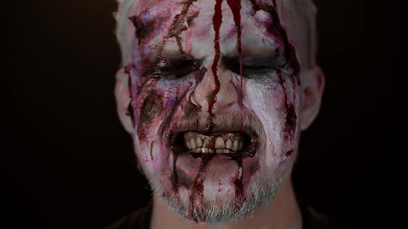 Closeup of Sinister Man with Horrible Scary Halloween Zombie Makeup Blood Flows and Drips on Face