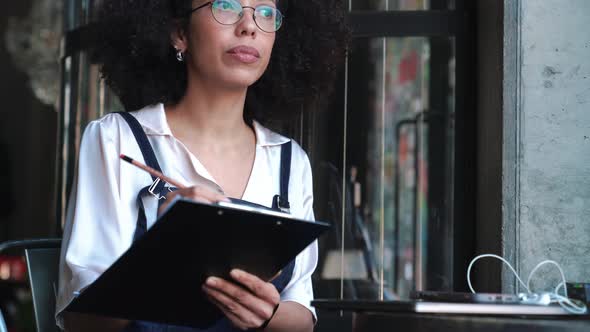 Concentrated female administrator writes down a list of goods