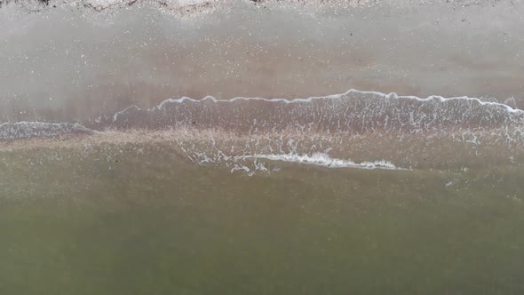 ocean waves breaking on sand beach shore aerial drone tracking