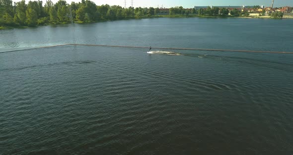 Aerial View of the Anchorage of the Cable Car Wake Park and an Athlete Cutting Through the Water on