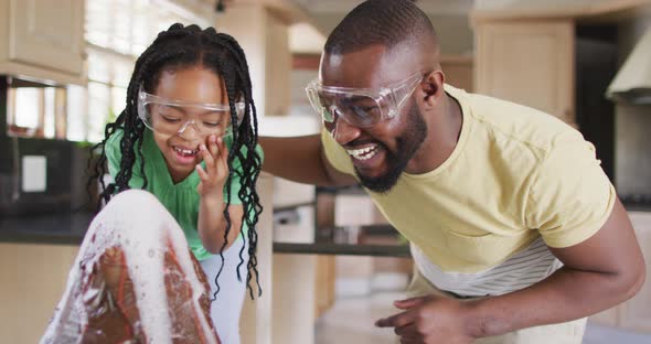 Happy african american father and daughter doing science experiments with makeshift volcano