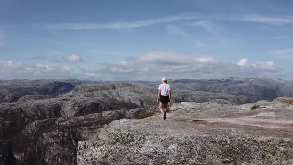 Aerial Shot of a Woman Walking By the Edge of a Cliff During a Morning Hike