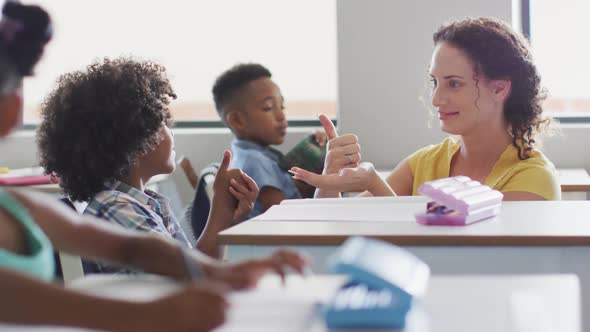 Video of happy caucasian female teacher learning math to african american boy alt