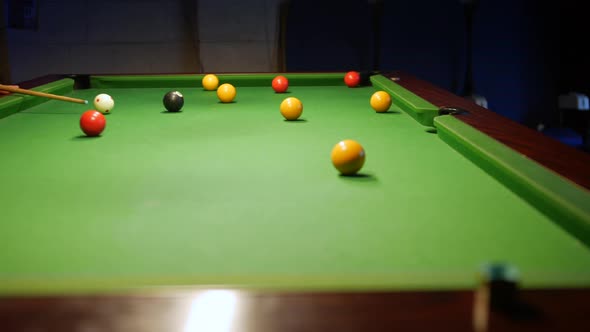 A man potting a yellow ball on a pool table in to the center pocket