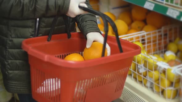 Woman in Gloves Picks an Orange