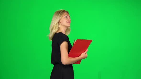 Woman with a Red Folder Goes Carefully Looking Around and Taking Notes, Chroma Key. Side View