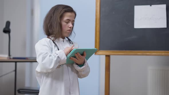 Female Caucasian Doctor with Tablet Standing Indoors Surfing Internet Thinking