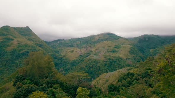 Clouds touch the peaks of mountains in central Cebu as drone flies towards the mountains