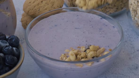 Woman Preparing Healthy Blueberry Smoothie Bowl with Blueberries Chia Seeds and Granola