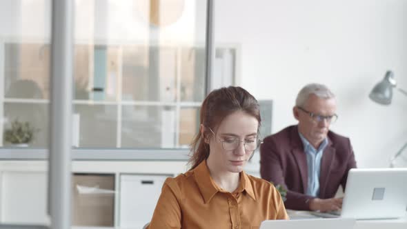 New Female Employee Posing at Office Desk with Anxious Smile