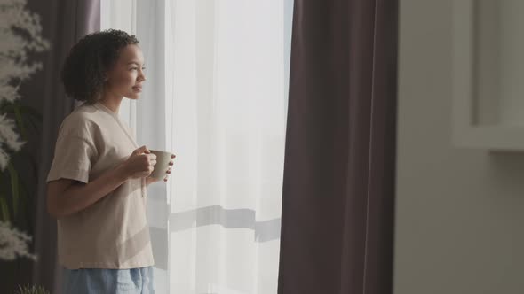 Biracial Girl Drinking Morning Coffee by Window