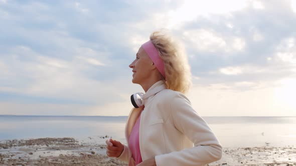 Close Up of Athletic Fitness Mature Woman Running on Beach.