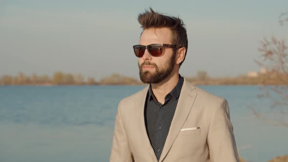 Businessman Walking On Nature.Handsome Businessman Enjoyng On River.Guy In Sunglasses Walks On Sand