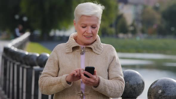 Attractive Old Woman of Retirement Age Using Modern Gadget Scrolling Looking Phone Screen