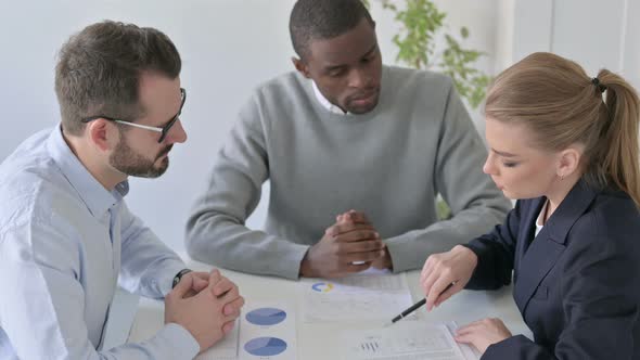 Businesswoman Explaining Reports to Male Colleagues in Office