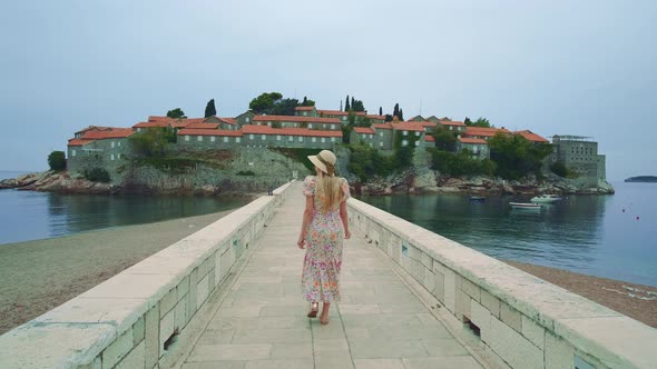 Back View of Elegant Woman Walking to the Old Castle Laid on Water