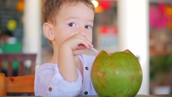 Cute Child Drinks a Coconut Trough a Straw, Close-Up. . Concept: Children, Happy Childhood, Summer