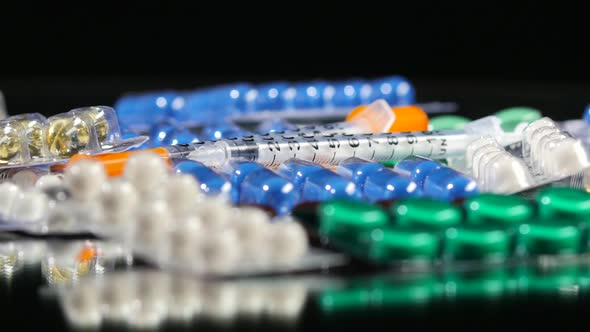 Some Different Contraceptive Pills and Two Syringes, Rotation, Reflection, Close Up, on Black