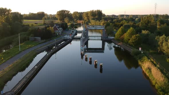 Water lock with trees reflection during golden hour in ascending drone view