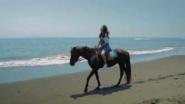 Cute Chinese Teenager Rides a Horse On The Beach In Bali