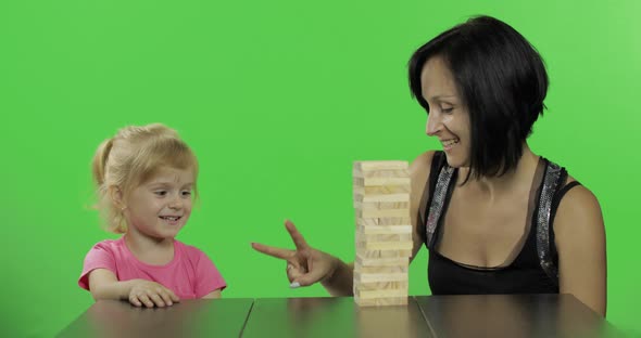 Mother and Daughter Plays the Jenga. Child Pulls Wooden Blocks From Tower