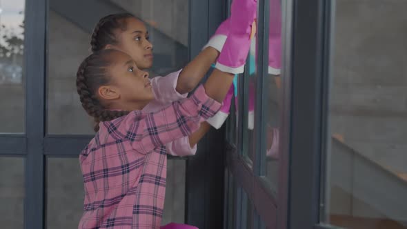 Girls Washing Window Glass with Cleaning Supplies