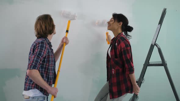 Excited Carefree Couple Having Fun Painting Wall