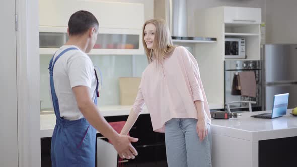 Young Beautiful Woman Discussing Fixing of Broken Kitchen Cabinet with Service Man