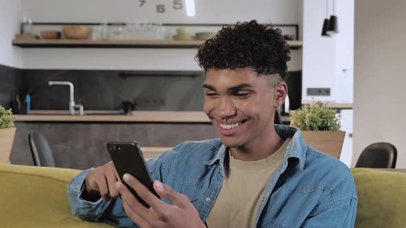 Happy Young Black Student Smiling Having Positive Emotions Looking on Screen of Smartphone Medium
