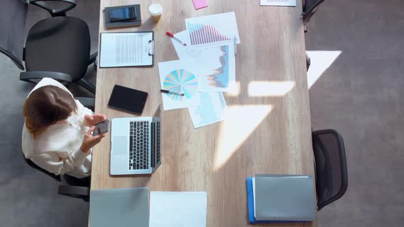 Manager Sits at Workplace Using Mobile