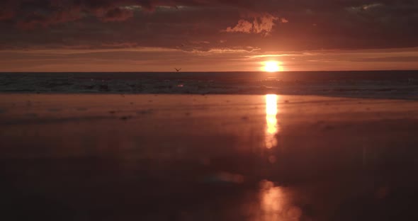 Waves breaking in slow motion in front of the sunset on Sylt