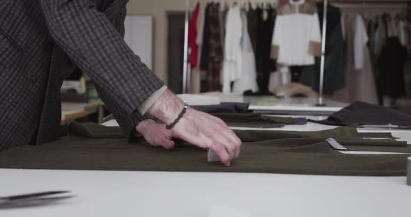 The Tailor Draws the Markings on a Fabric with Chalk on Desktop in Dress Atelier