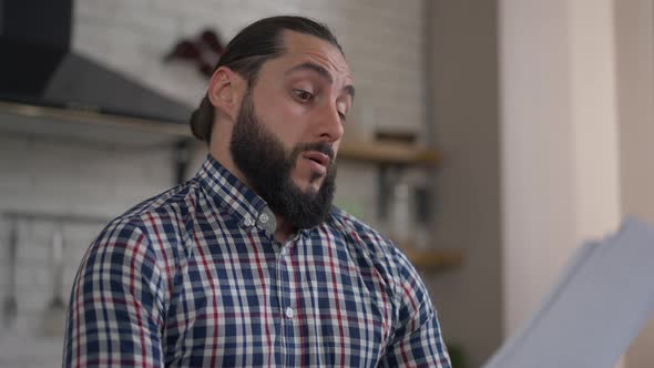 Smart Thoughtful Middle Eastern Man Examining Documents Sighing in Home Office