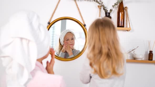 Little Girl with Mom Applying Creme Near Mirror