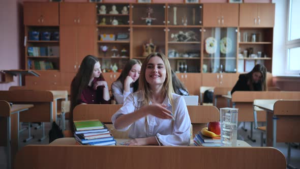 A Girl Student Sitting at a Desk Raises Her Hand in the Class