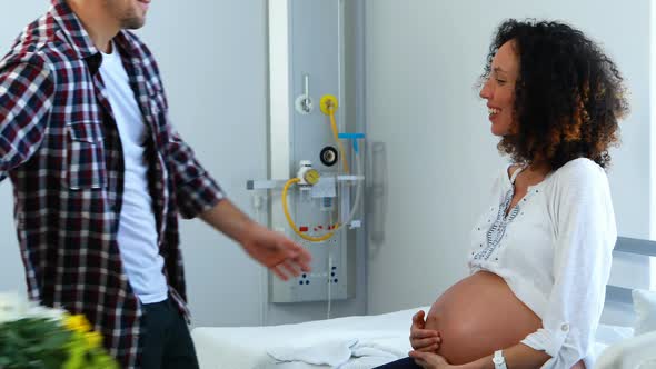 Man offering bunch of flowers to his pregnant woman in ward