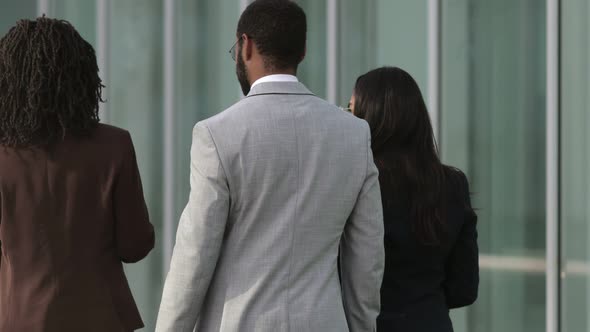 Back View of Three People Wearing Suits Walking Near Building