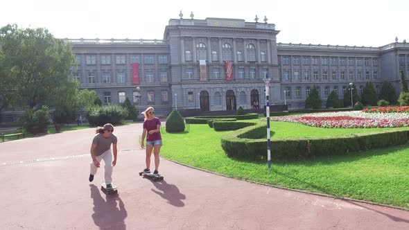 Man on a skateboar and woman on a longboard riding in the city