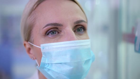 Headshot of Concentrated Blond Caucasian Woman in Covid Face Mask Looking Away with Grey Eyes