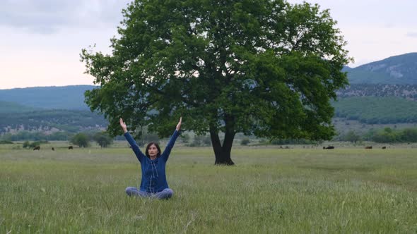 Woman on a Yoga Mat To Relax in a Field Near a Lonely Oak