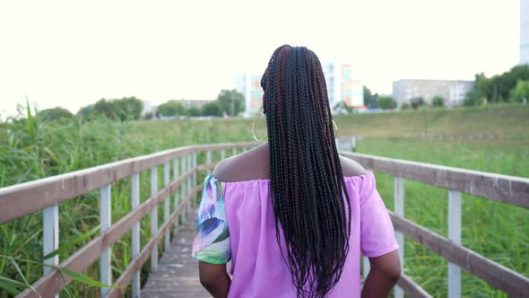 African Woman with Long Afro Braids Spinning on a Wooden Bridge