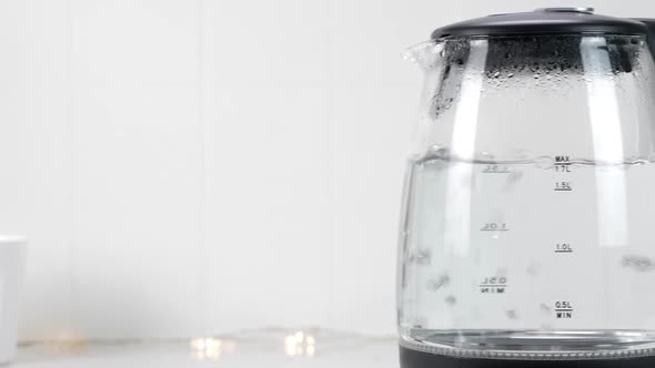 Boiling Water in Glass Kettle in White Kitchen Interior