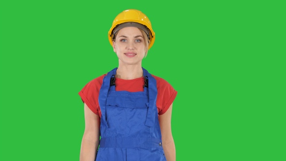 Young woman in yellow hardhat walking on a Green Screen