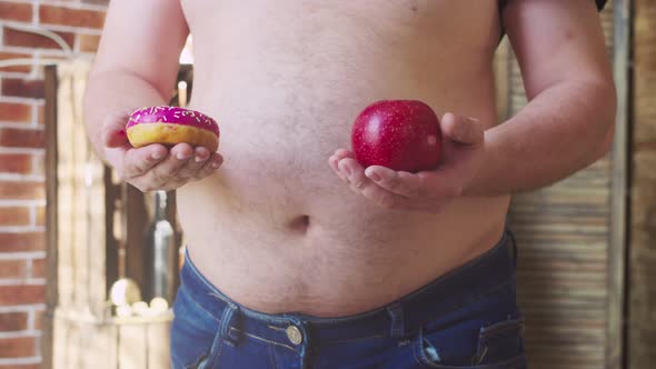 Overweight Man Chooses Between a Doughnut and an Apple