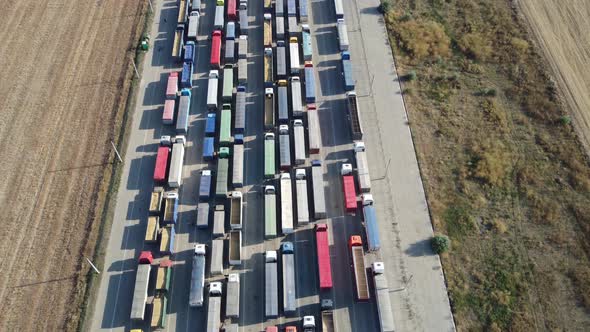 The drone flies over a long line of trucks standing in the port terminal waiting to be unloaded.