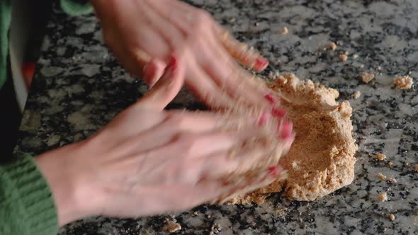 Dolly in of woman hands mixing together pieces of batter to form a cookie dough