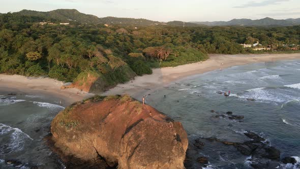 Father and son standing on a large beach rock at playa Grande near Tamarindo, Costa Rica. Still aeri