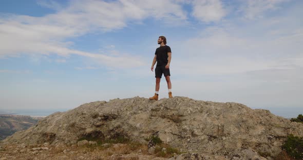 Boy spreads his arms and enjoys life on the top of a mountain