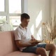 A man is sitting on a sofa and begins to read a book - VideoHive Item for Sale